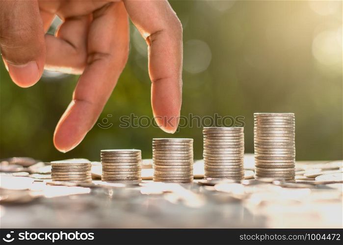 The coins are arranged in five rows. As the men's fingers are leaping. With the bokeh scene and morning sun shining.