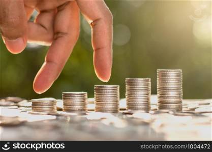 The coins are arranged in five rows. As the men's fingers are leaping. With the bokeh scene and morning sun shining.