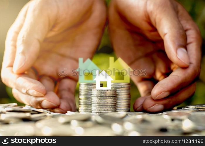 The coins are placed together and there is a small white paper house on top. As the two men&rsquo;s hands are encircled.