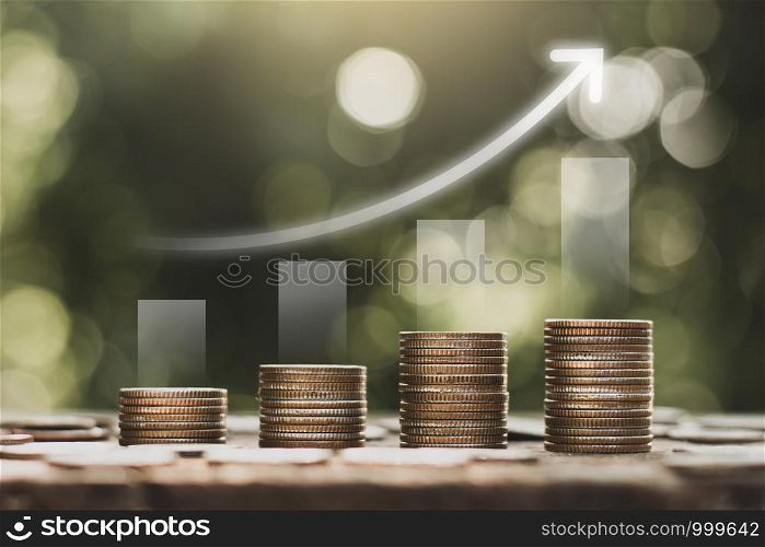 The coins are stacked on an old wooden table and have growth graphs on top,financial growth ideas.