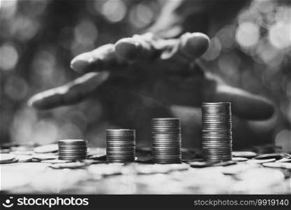 The coins were stacked four in a row and there was a man’s hand, a businessman, about to grab.