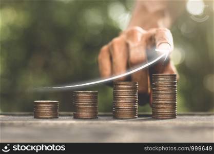 The coins were stacked on a black wooden table and had the hands of men touching the digital arrow technology, the concept of financial growth.