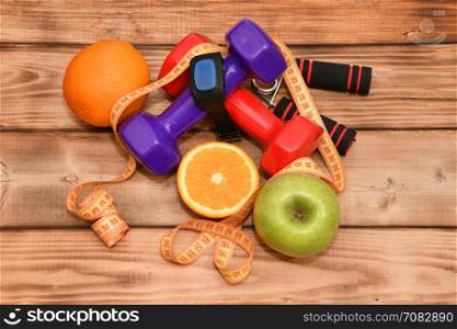 The concept of a healthy lifestyle, sports and diet. Dumbbells, smart watches, fruit, measuring tape