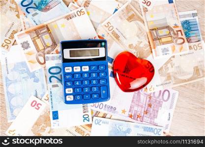 The concept of calculating medical expenses. The calculator and the figure of heart on the Euro banknotes
