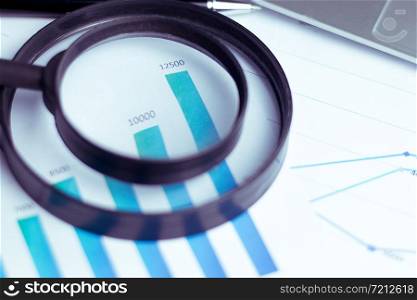 The concept of the company&rsquo;s sales analysis, charts and graphs looked through the magnifying glass.