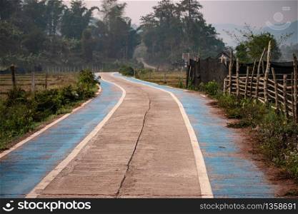 The concrete road in the countryside has blue paths for bicycles in the valleys.