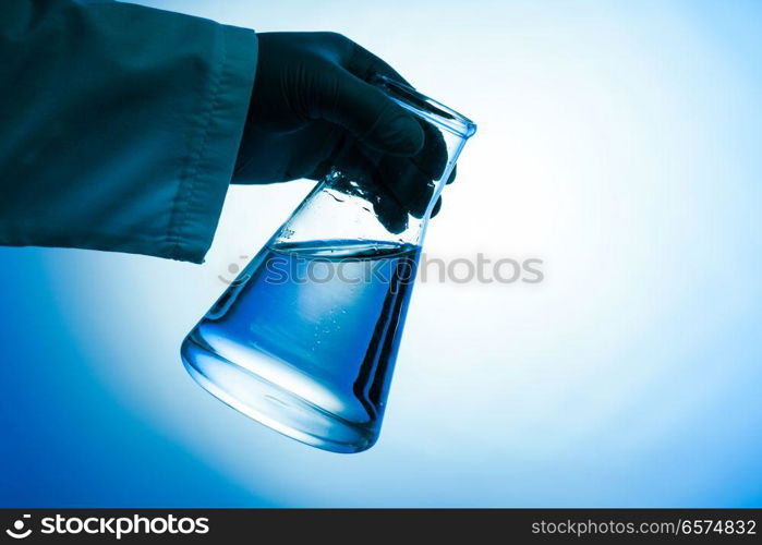 The conical flask with green liquid in the hand - laboratory glass. The conical flask