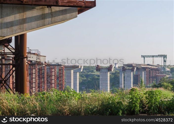 the construction of a bridge across the river with the supports, structural elements, cranes