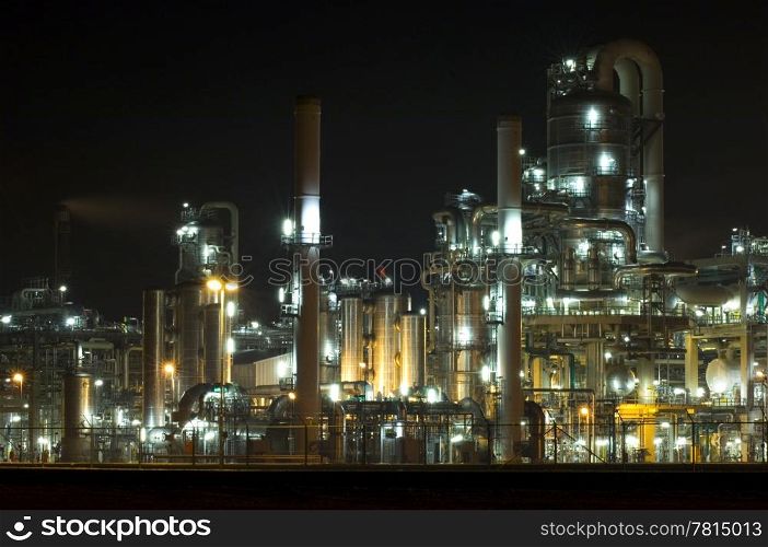 The converters, pipes, tubes chimneys and structures of a illuminated petrochemical plant at night