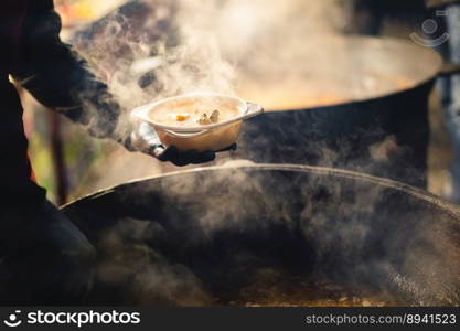 the cook fills a bowl with hot street food