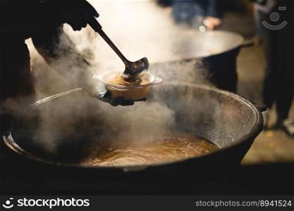 the cook fills a bowl with hot street food