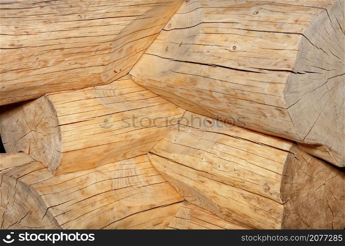 The corner joint of the walls of a wooden house, peeled from the bark of the logs. Close-up. Pronounced texture of wood with longitudinal and transverse cracks.. Articulation of logs without bark in the shape of an angle when building a log hut.