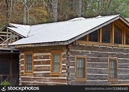 The corner of a log house showing windows and roof.