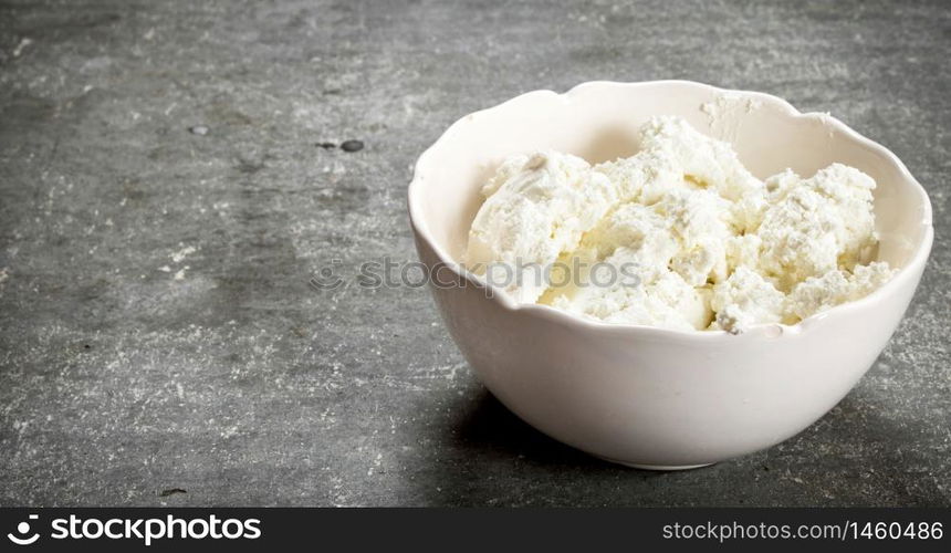 The cottage cheese in a bowl. On the stone table.. The cottage cheese in a bowl.