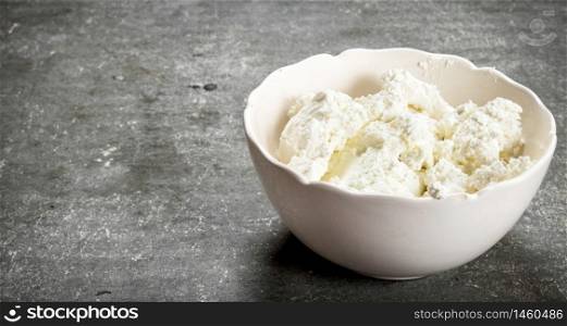 The cottage cheese in a bowl. On the stone table.. The cottage cheese in a bowl.