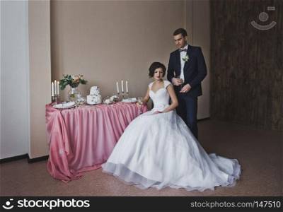 The couple in beautiful outfits sitting at the beautiful table.. The bride and groom sit at the Banquet table 6449.