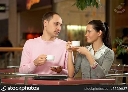 The couple talks in cafe behind a coffee cup