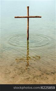 The cross is standing in the water, symbol for washing off our sins by Jesus, who died on the cross for all people