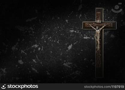 The Crucifix of Jesus Christ hanged on black concrete wall background with copy space for your text, christian background