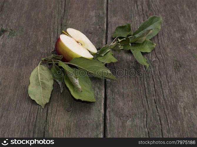 the cut apple with leaves on an old wooden table, a subject fruit