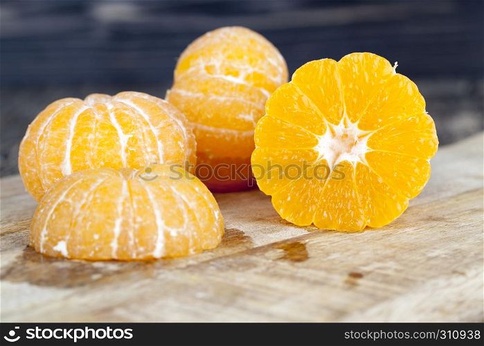 The cut peeled mandarin on the cutting board, juice spreads to the board. sliced tangerines