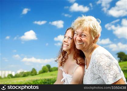 The daughter and elderly mother against the sky and park