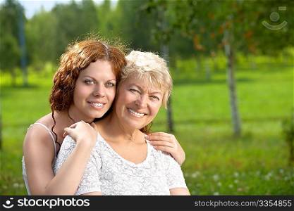 The daughter and mother in embraces in a summer garden