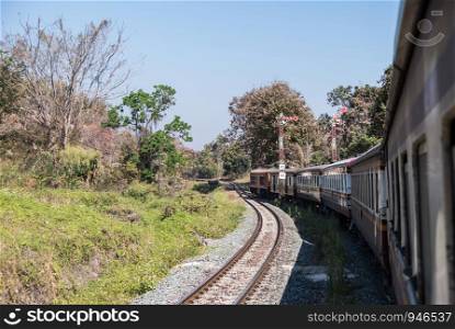 The diesel-electric locomotive of the express train is moving pass the signal pole of the rural station on the high mountain, northern line of Thailand.