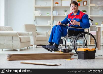 The disabled man laying floor laminate in office. Disabled man laying floor laminate in office
