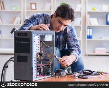 The disabled man on wheelchair repairing computer. Disabled man on wheelchair repairing computer