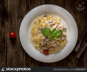 the dish of mushrooms and noodles decorated with a leaf of lettuce on wooden background, top view. dish on a wooden surface