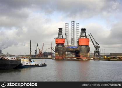 The dismantling of an oil rig at a dry dock in the midst of a busy commercial harbor