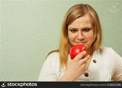 The dissatisfied girl looks at a red apple