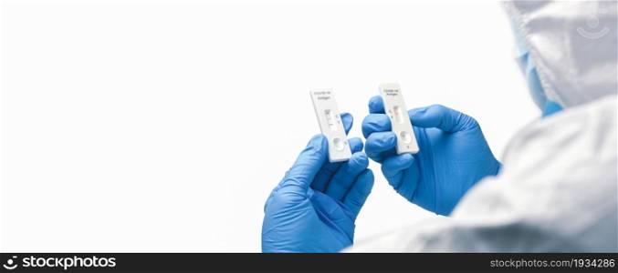The doctor compares tape from a rapid antigen test kit for a covid-19 result, horizontal copy space on white background
