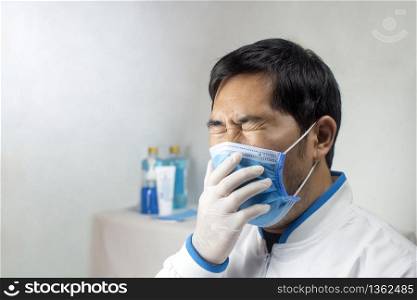 The Doctor coughing in a medical mask at a white room of hospital.