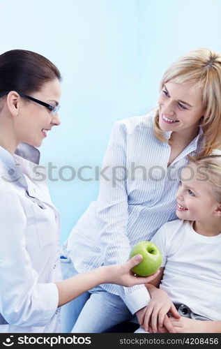 The doctor gives the child a green apple