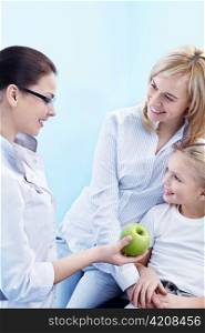 The doctor gives the child a green apple
