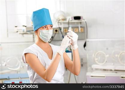 The doctor in gloves with a syringe against a hospital interior