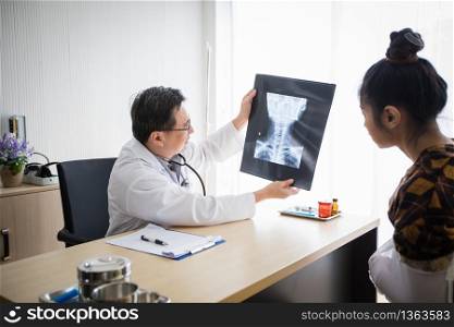 The doctor is explaining about the brain X-ray results to a female patient in his office at Hospitals