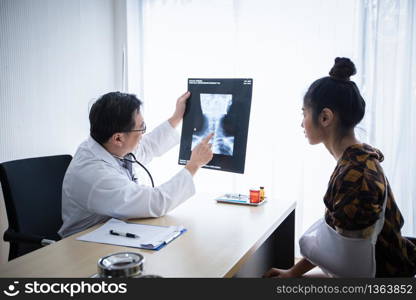 The doctor is explaining about the brain X-ray results to a female patient lying in bed at a hospital