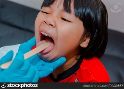 The doctor uses a tongue depressor to examine the child"s tongue.