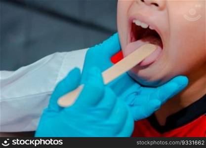 The doctor uses a tongue depressor to examine the child"s tongue.