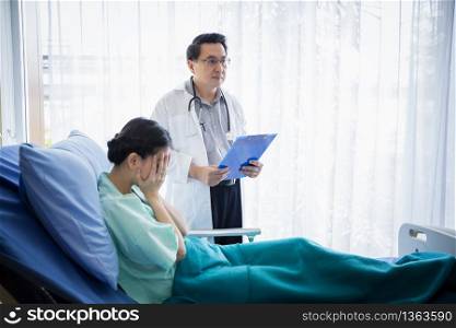 The doctors are asking and explaining about the illness to a female patient lying in bed at a hospital.