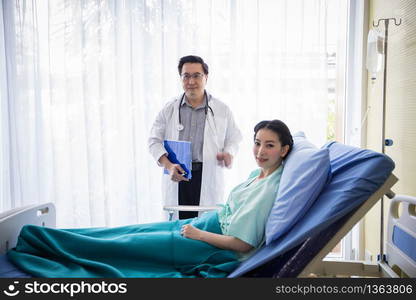 The doctors are asking and explaining about the illness to a female patient lying in bed at a hospital.