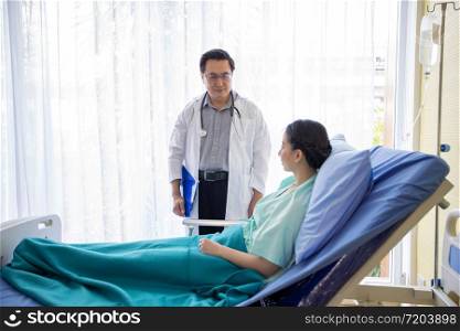 The doctors are asking and explaining about the illness to a female patient lying in bed at a hospital.