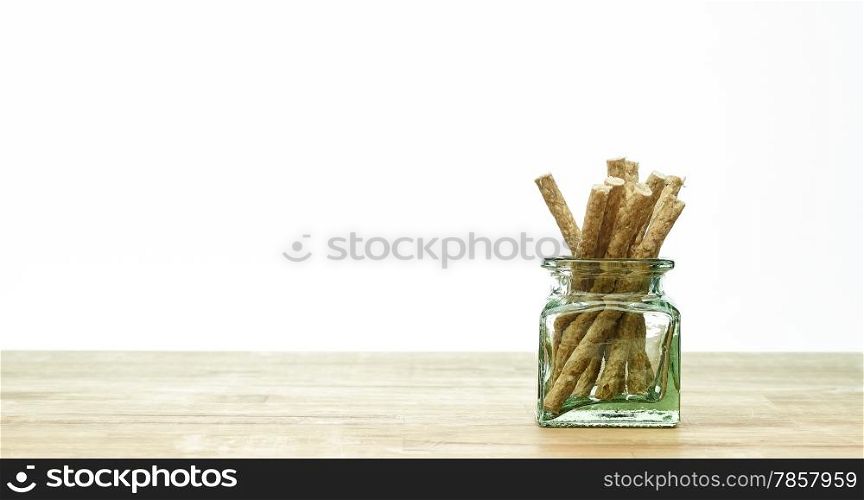 The dog tidbits and a glass container on the wooden table, white background and copy space.
