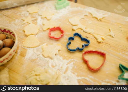 The dough cuted out by cookie cutters, nobody. Heart and gingerbread man pastry templates on the table