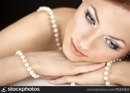 The dreaming woman with a pearl necklace on the bared shoulders