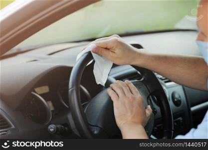 the driver cleans the steering wheel of his car with an antibacterial cloth. Antiseptic, Hygiene and Healthcare concept. selective focus.. the driver cleans the steering wheel of his car with an antibacterial cloth. Antiseptic, Hygiene and Healthcare concept. selective focus