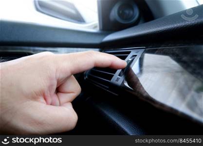 The driver hand adjust the wind speed of the car air vent in a car